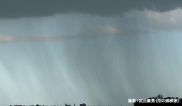 雨のすじを撮影した写真。雲の動きや風によって雨のすじが曲がっていることが分かる