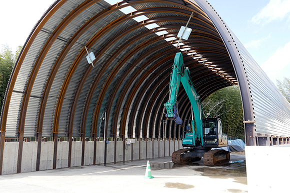 鉄建建設株式会社 建設技術総合センター内に構築された模擬トンネル。延長21m、幅10.2m、高さ7.2mで、バックホーは0.8m<sup>3</sup>クラスを使用した